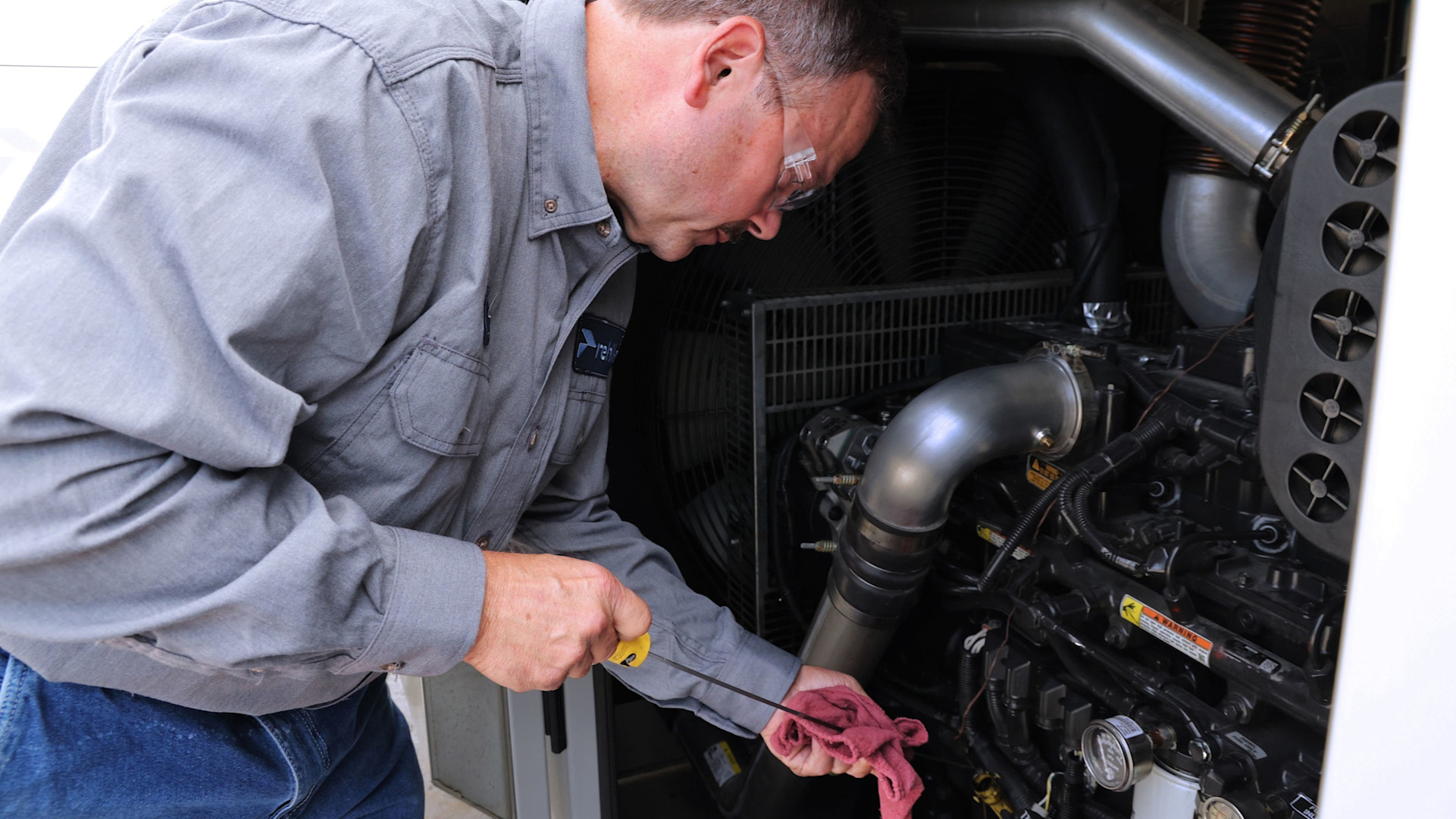 Male professional working on a generator wearing grey shirt