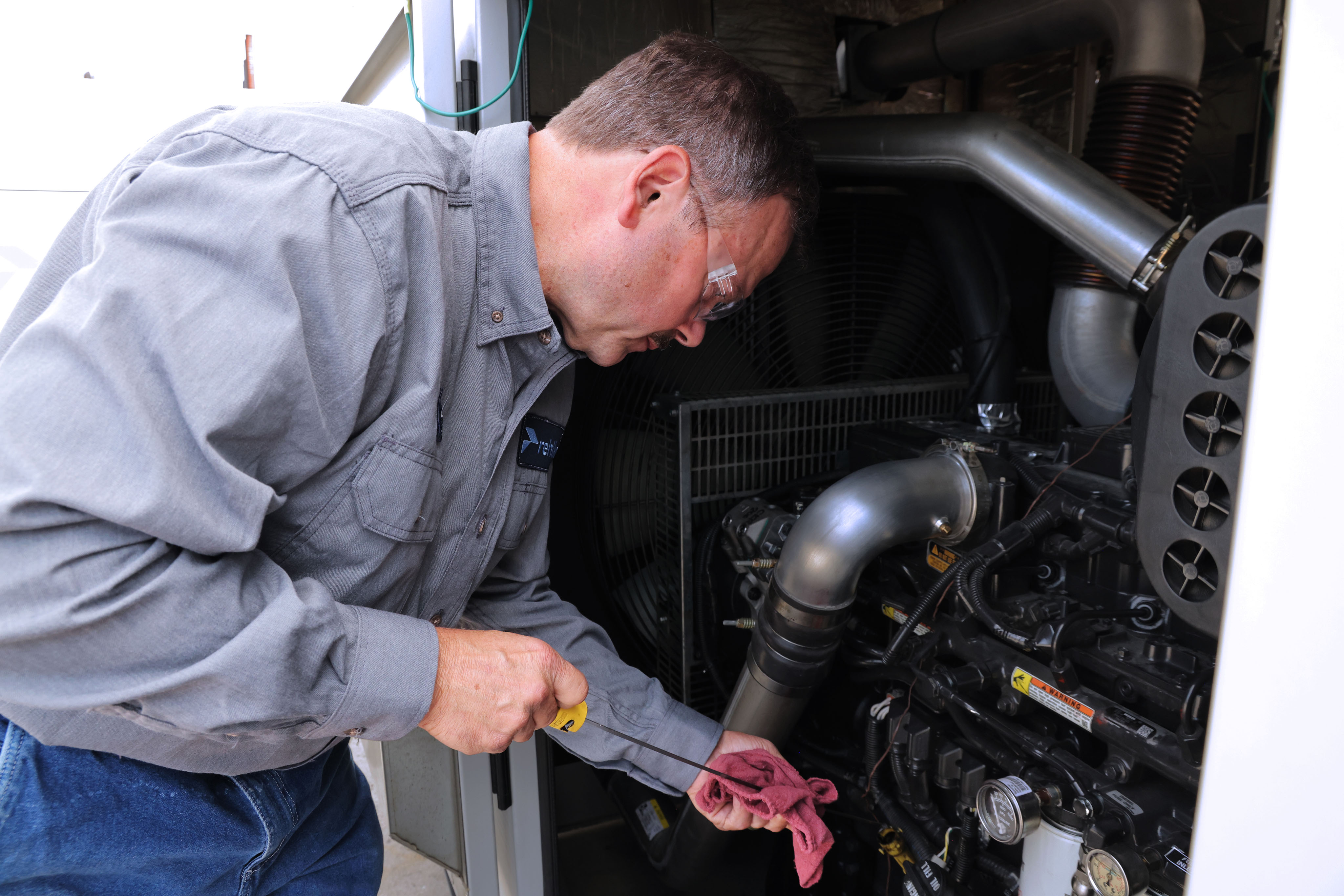 Male professional working on a generator wearing grey shirt