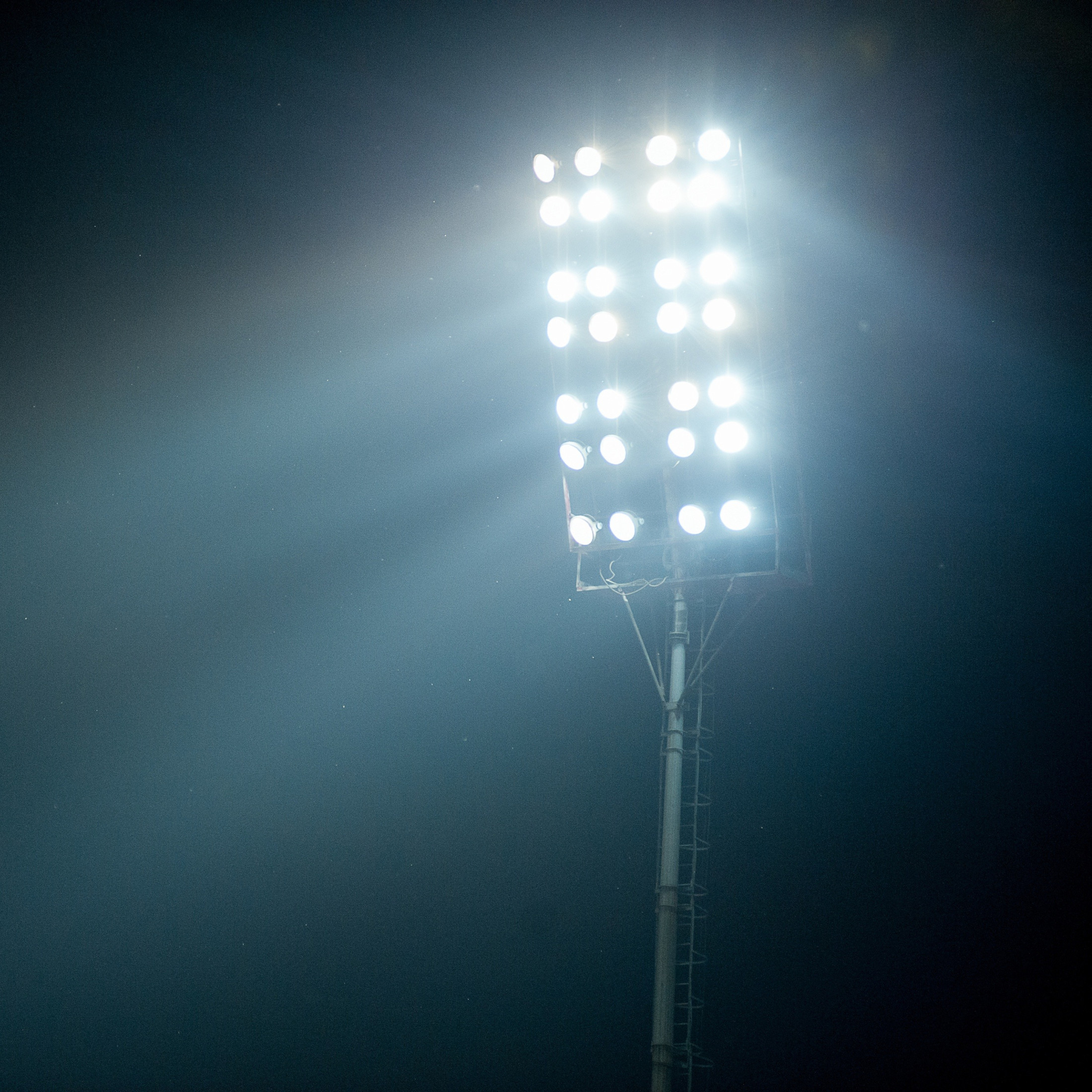 Outdoor floodlight pole illuminated at night.