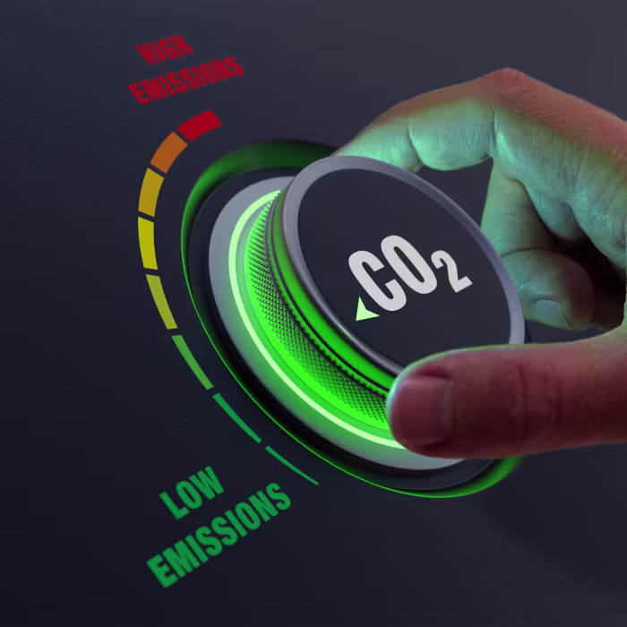 Hand turning a dial button with label CO2 and low emissions indicator on the left and high emission indicator on the right.