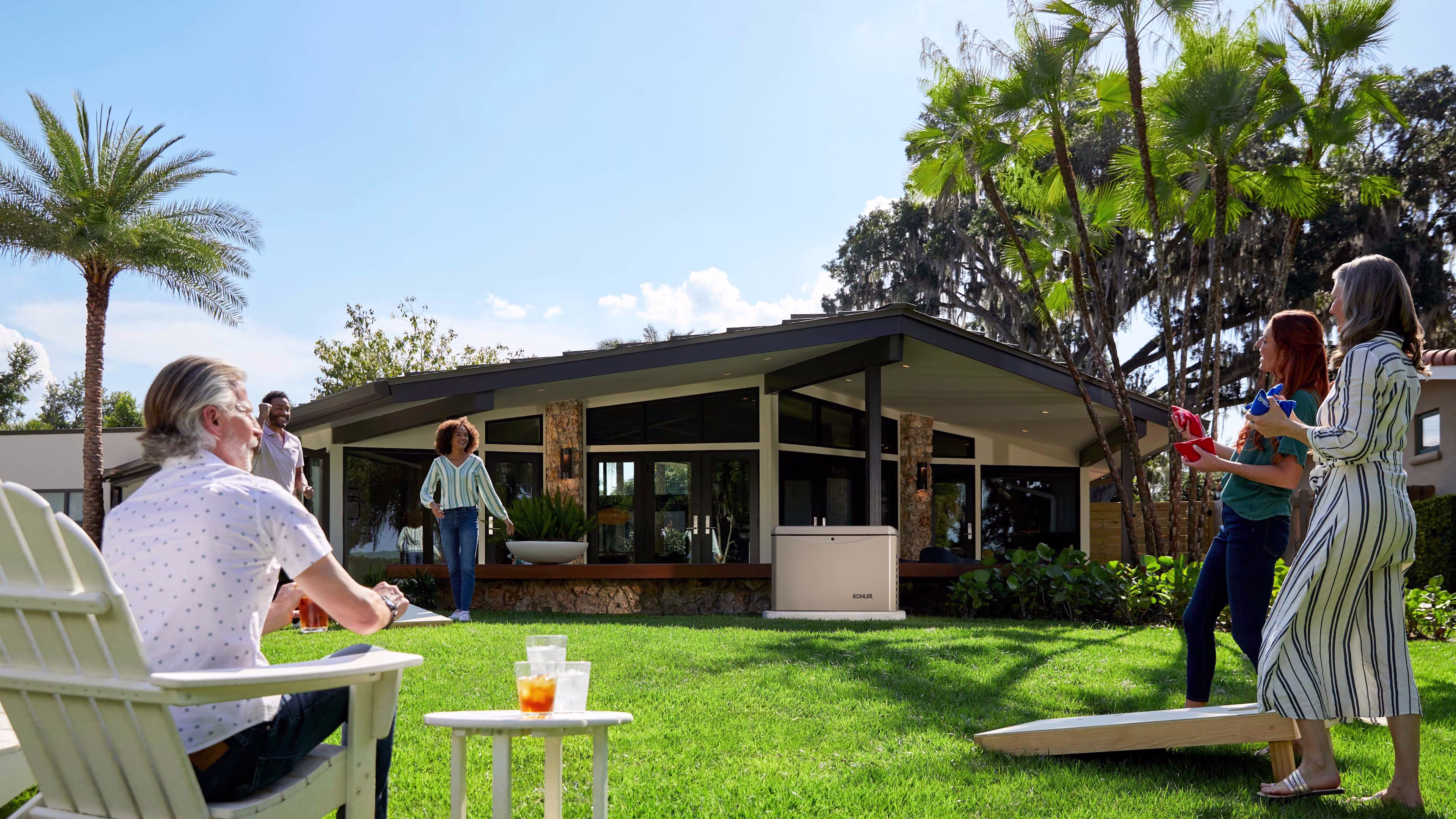 A family playing in the backyard in a sunny day with a Kohler home generator near the house.