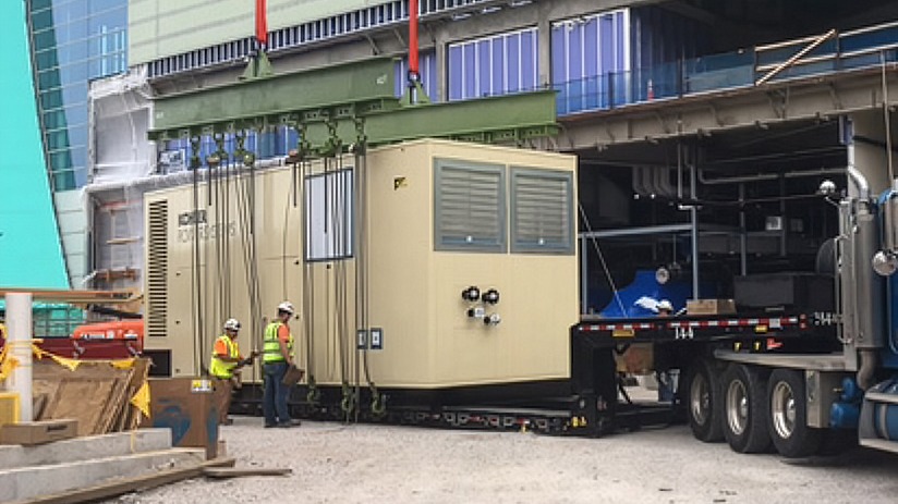  Workers preparing a Rehlko generator to be lifted in a sports arena.