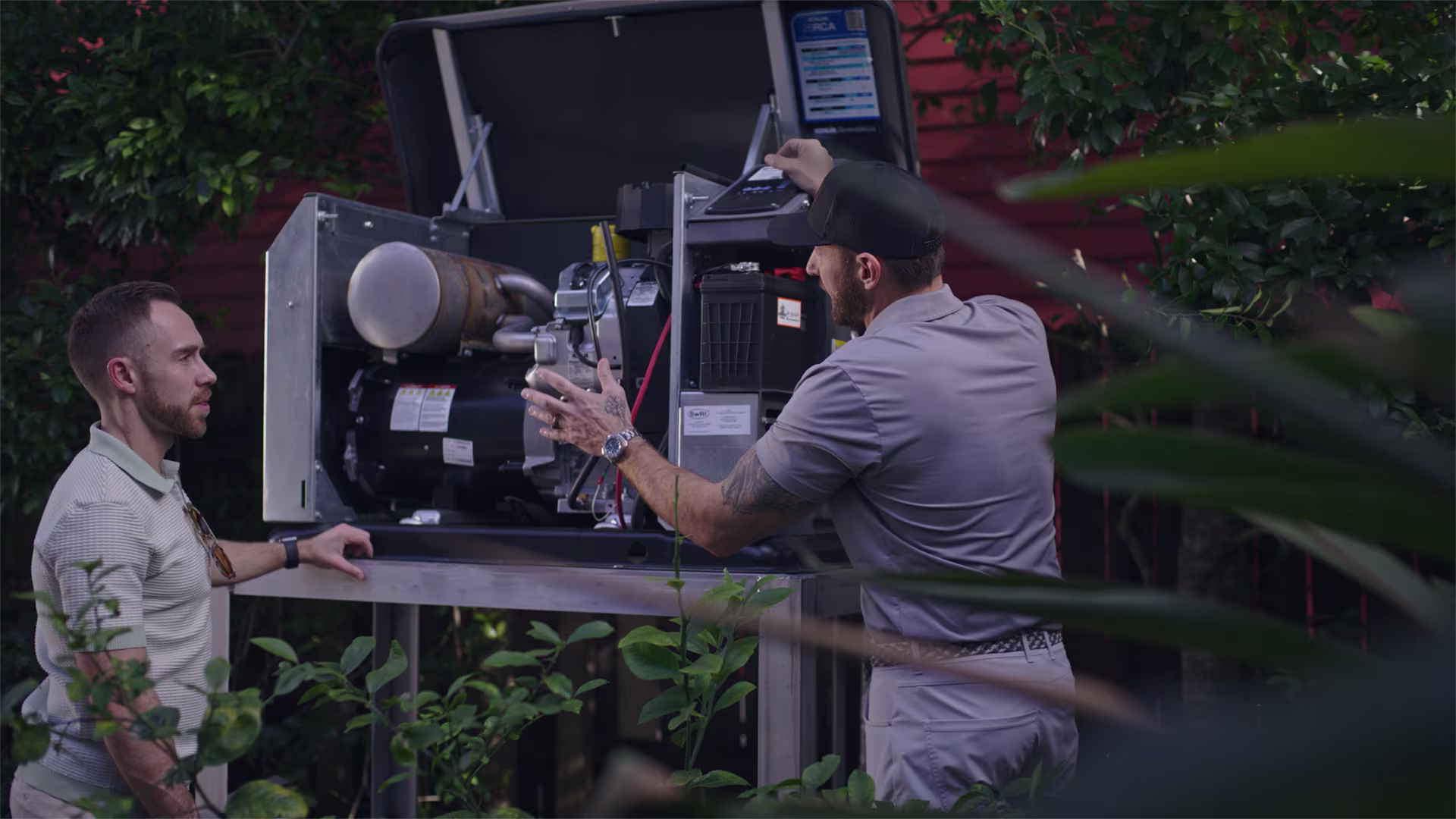 Two men in front of an open generator