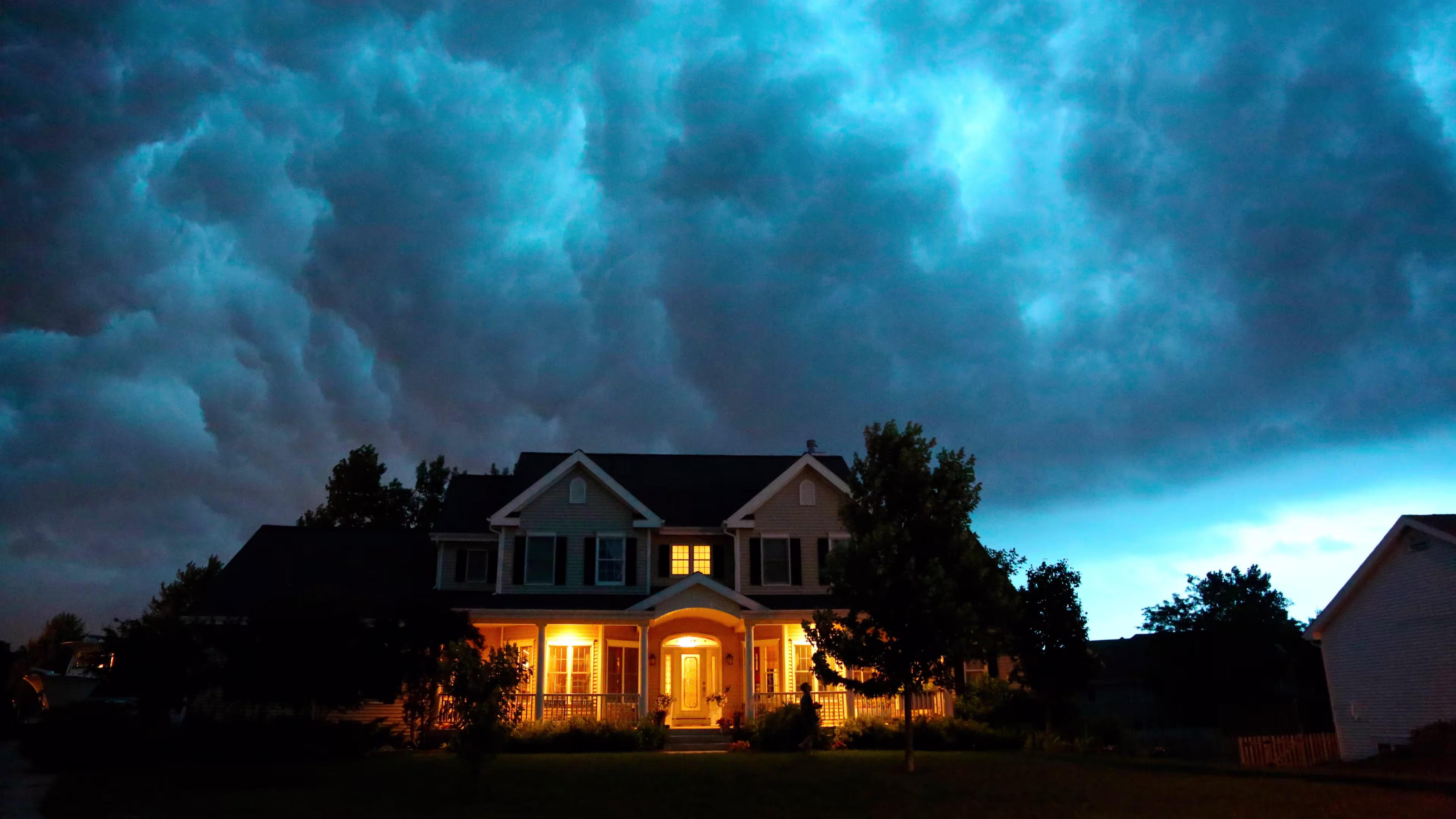 House with lights on, blue cloudy sky, storm sky
