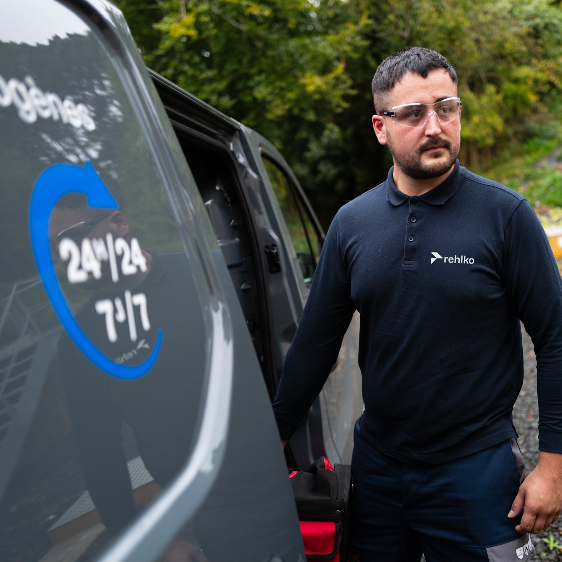 Man using a Rehlko t-shirt besides a car.