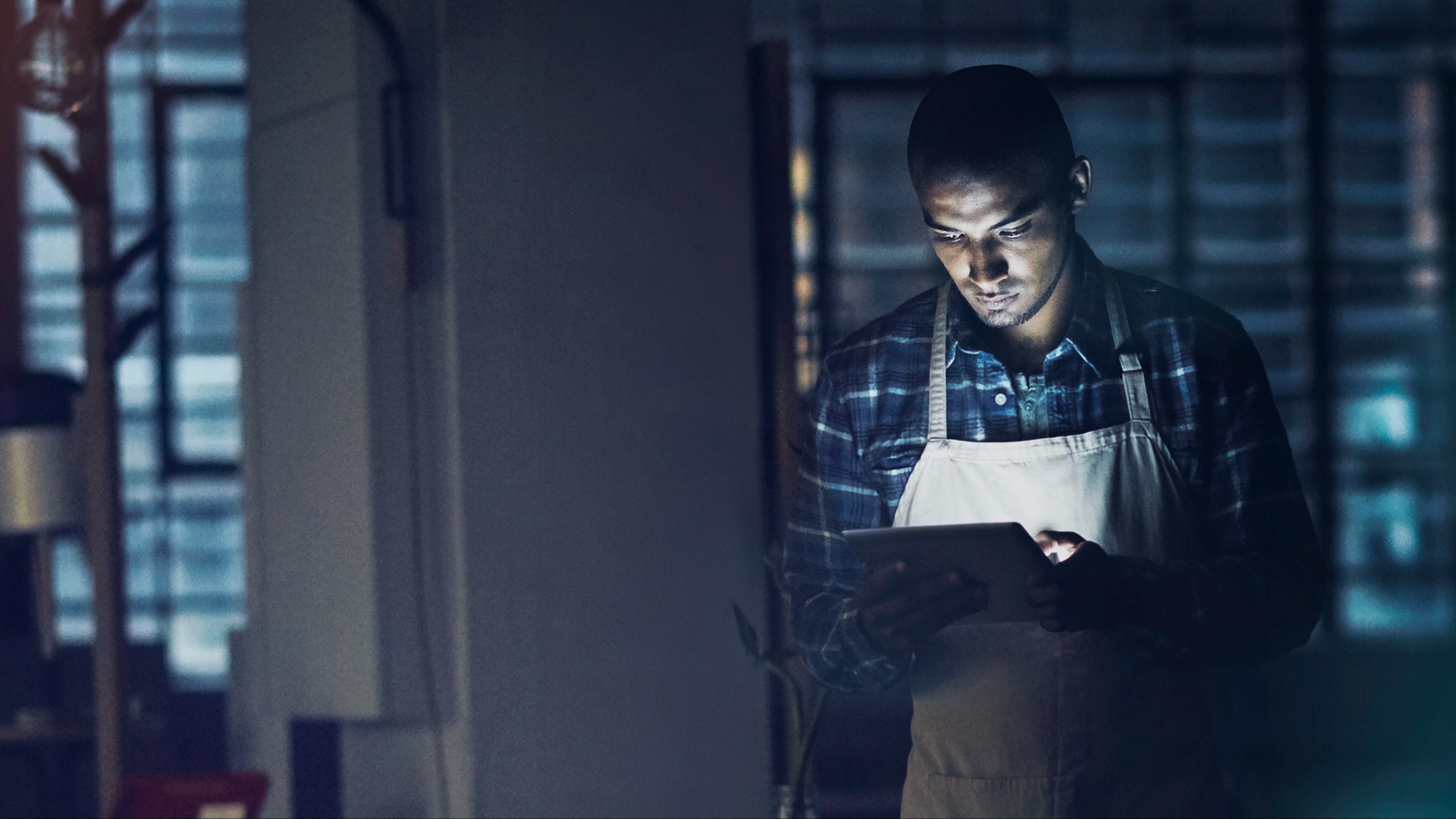 Man in a dark room looking at a tablet