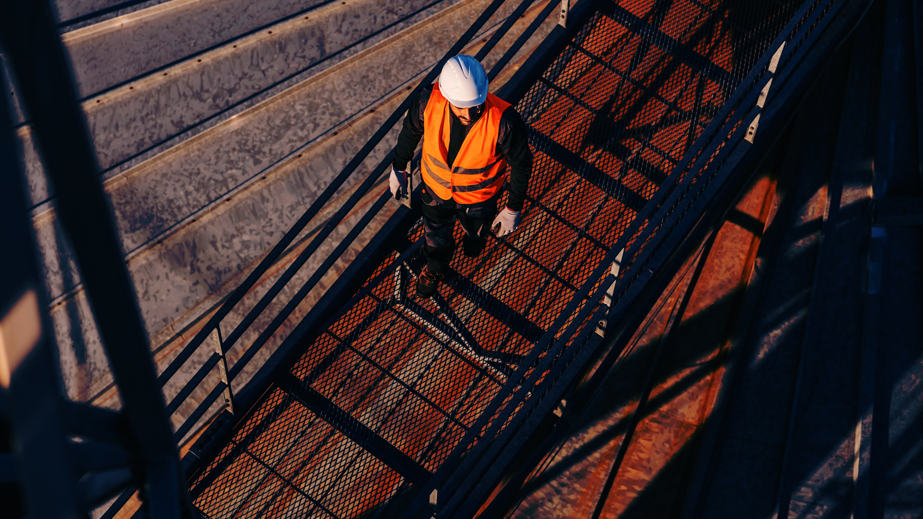 Man in orange safety vest on top of a metal structure