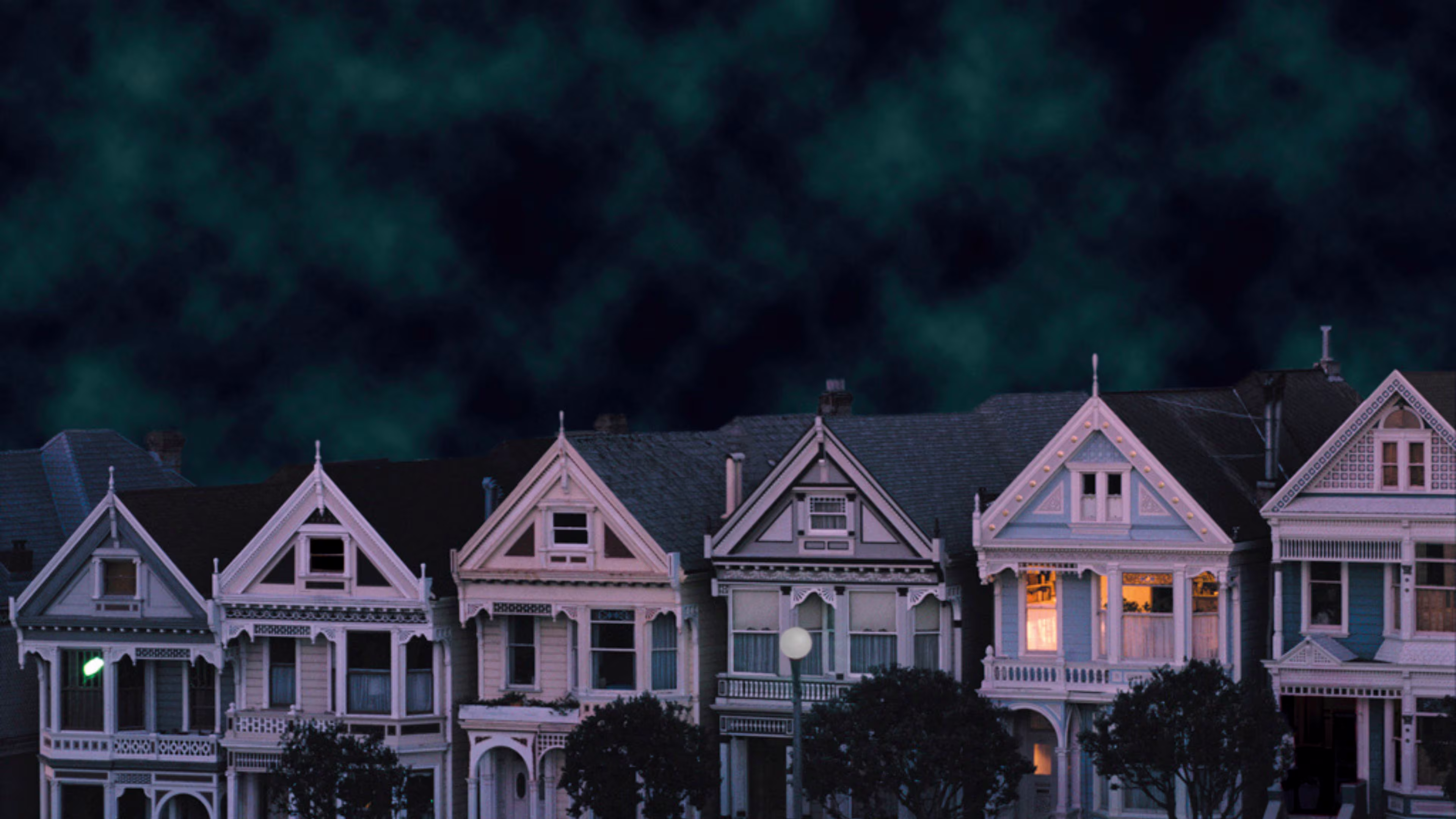 Row of six town houses at night with heavy sky.