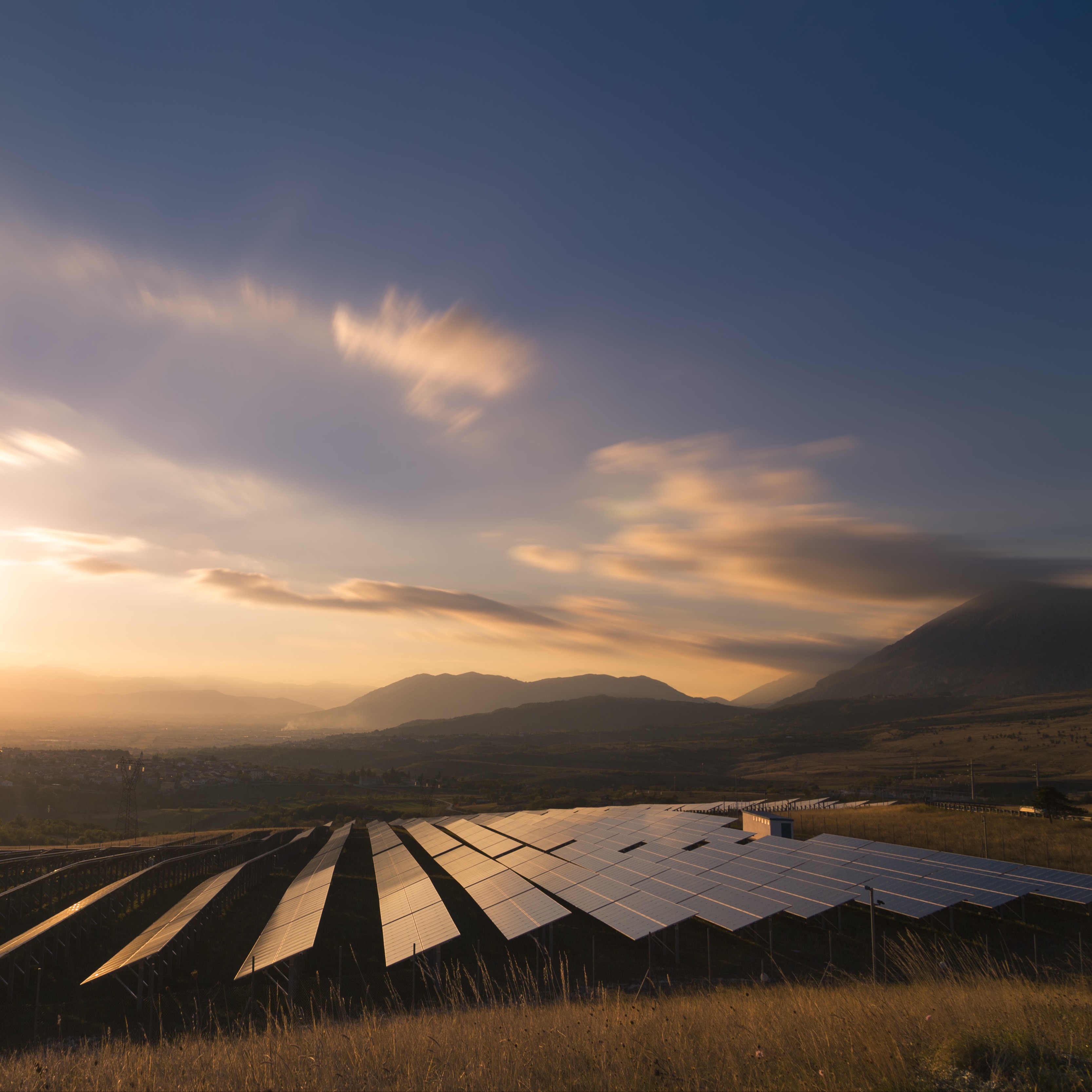 Solar panels in field with sun setting in background