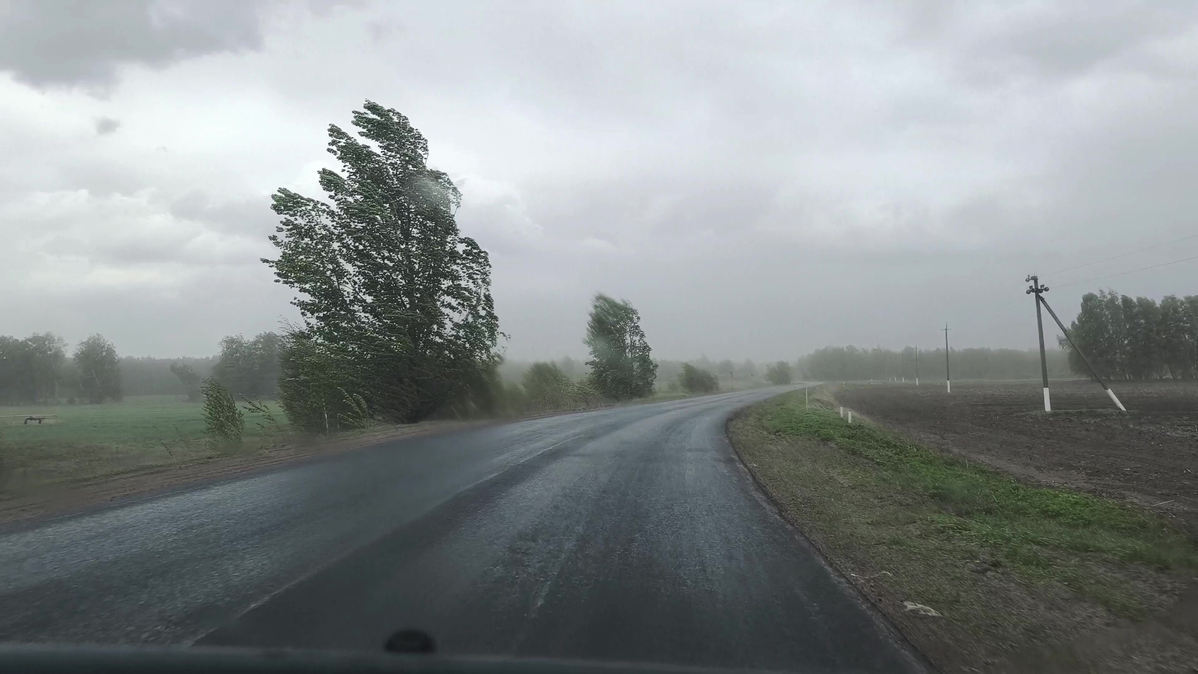 Vehicle driving through hurricane storm with low visibility on highway during extreme weather conditions.