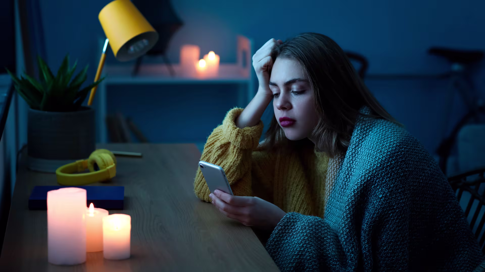 Woman in a dark room with candles and smartphone