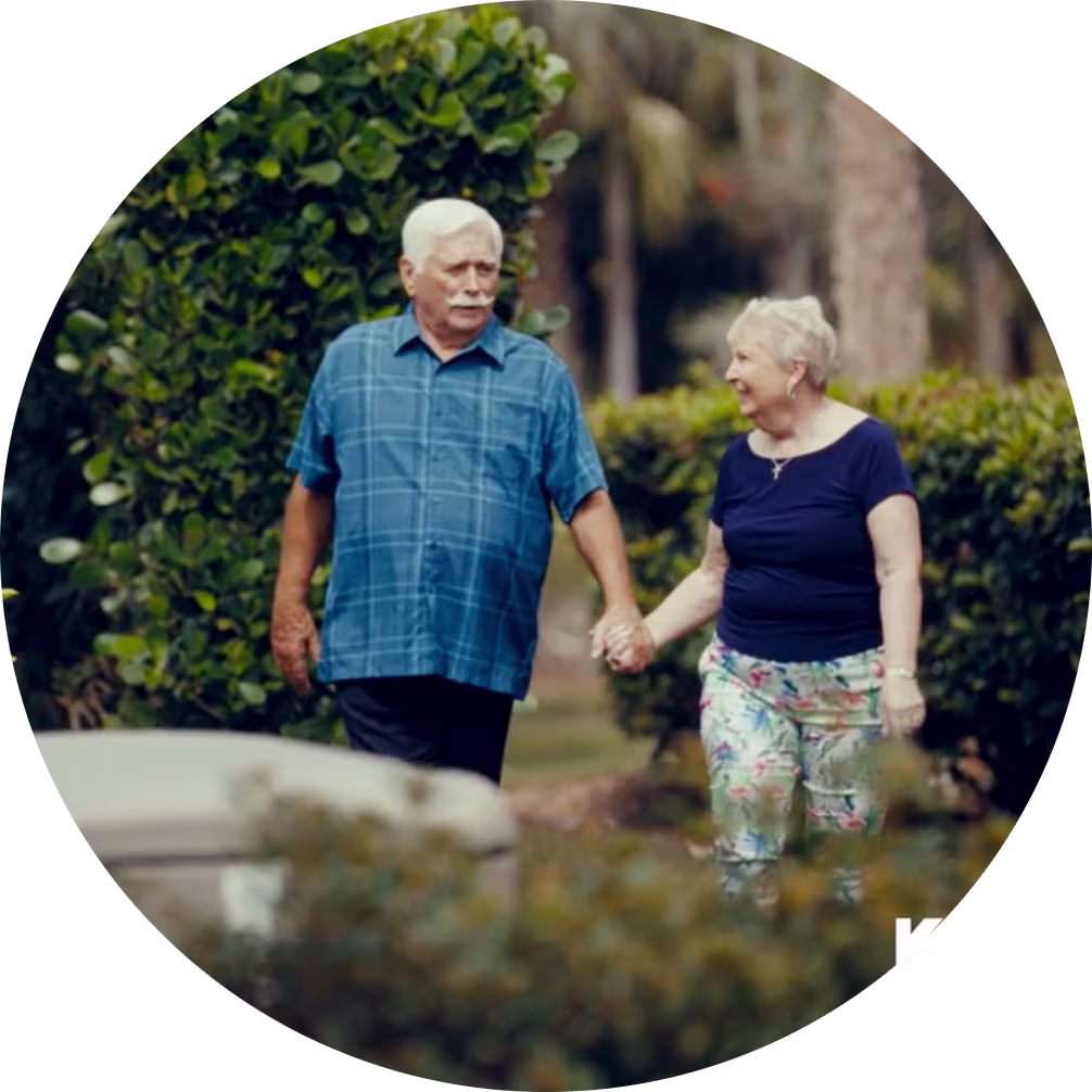 Elderly couple, walking holding hands through their yard in front of a Kohler home generator.