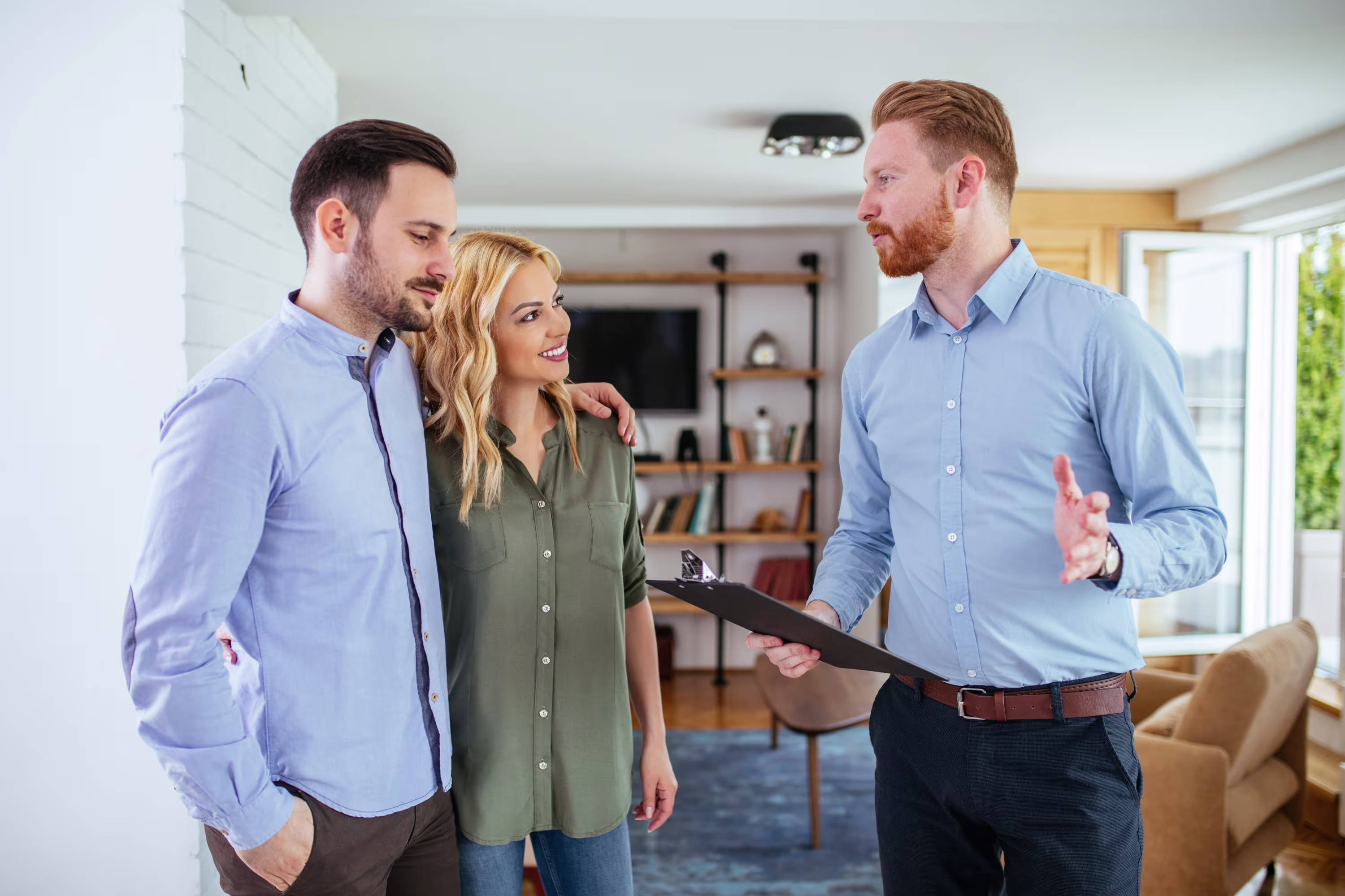 A man with a clipboard who appears to be a contractor talking to a man and woman in their home