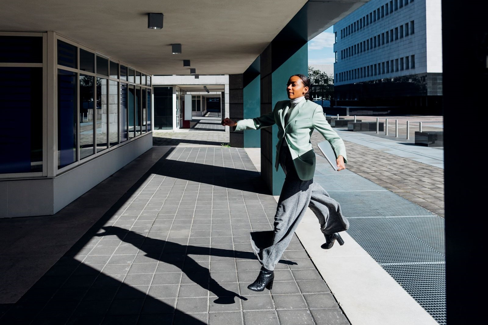 Woman in business clothing running to enter a building.