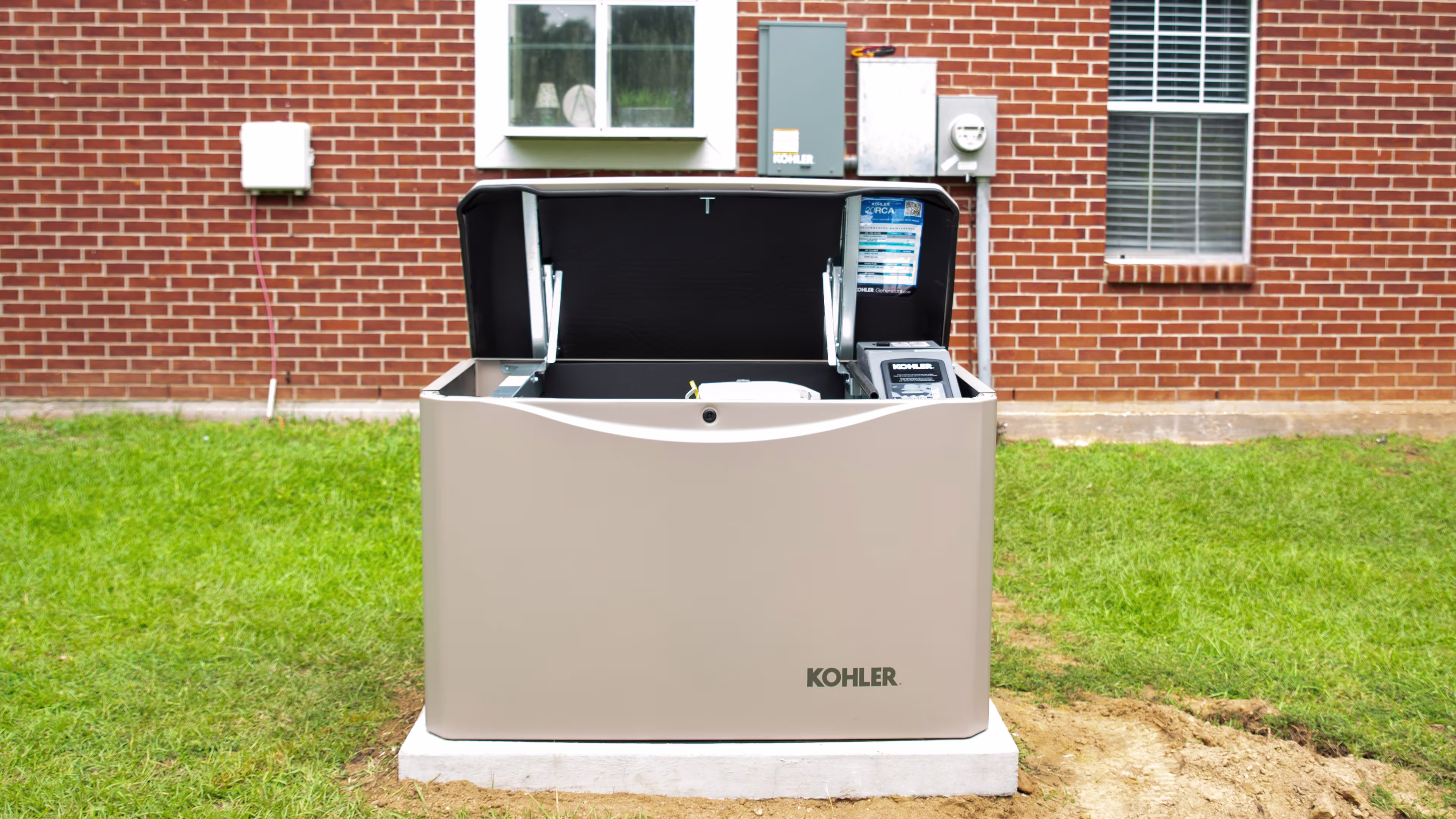 Home generator with the lid open on the side of a brick house