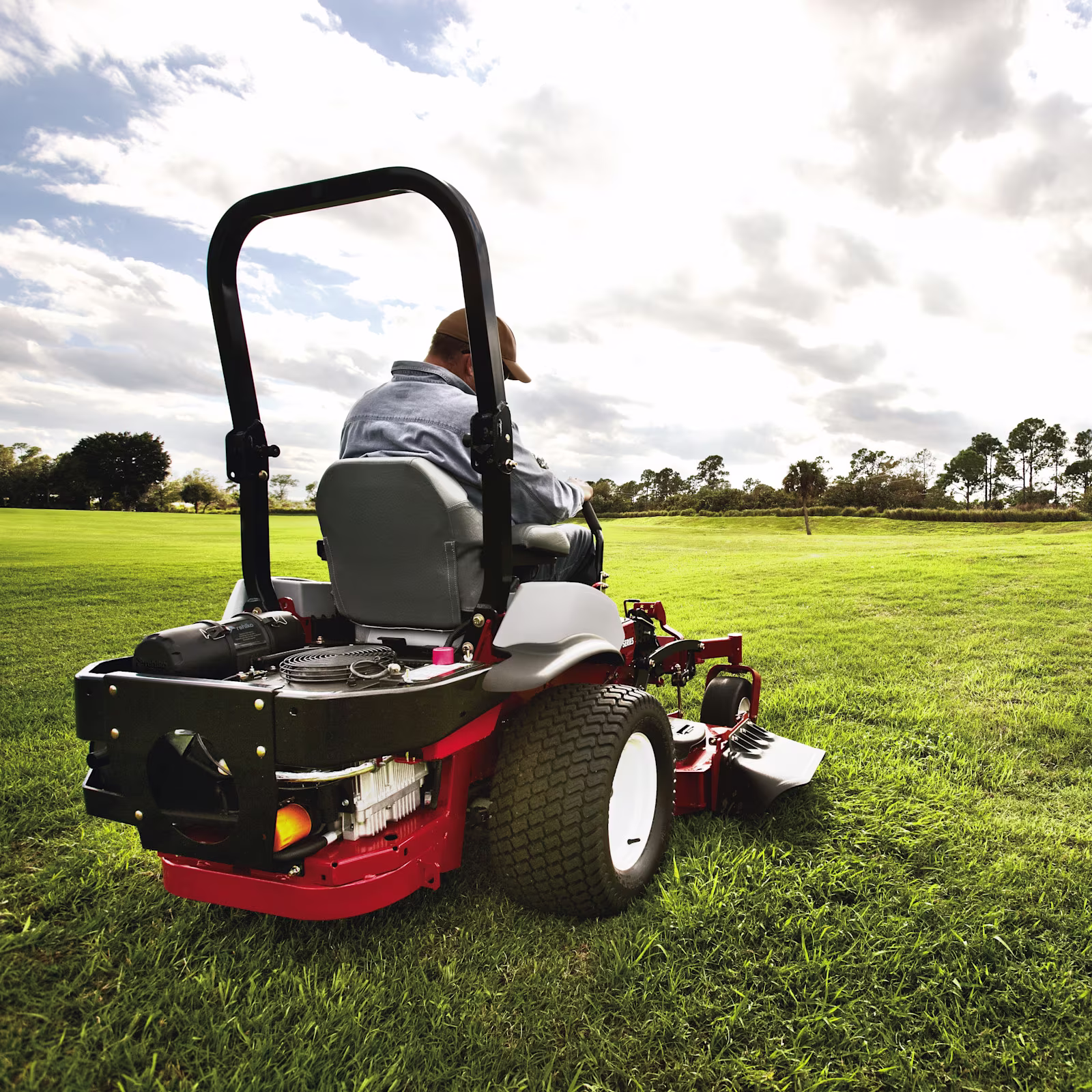 Red lawnmower with Rehlko engine on a green grass field. 