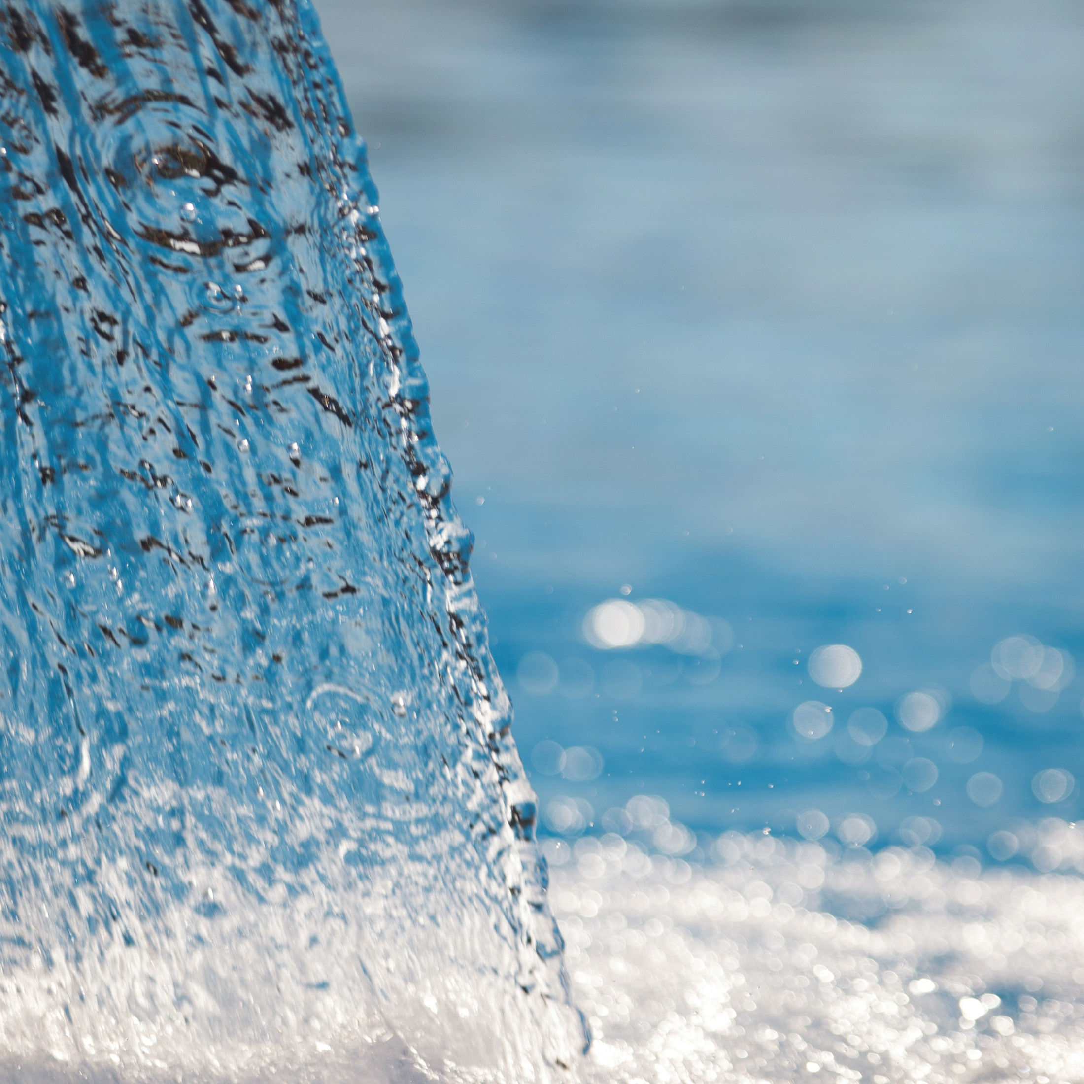 Close-up of water splashing into a wide, deep container.