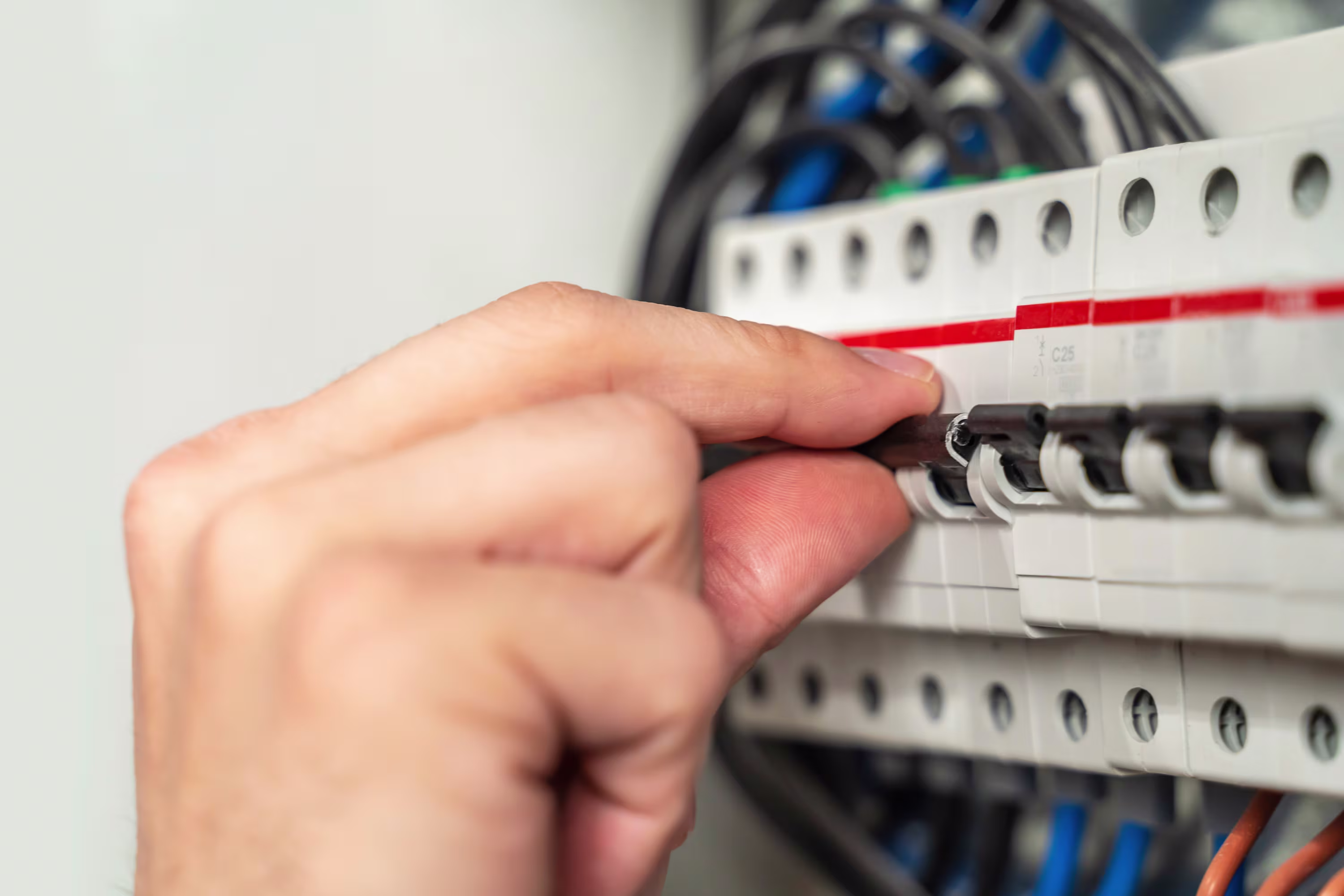 A person's hand on a bank of circuit breakers.