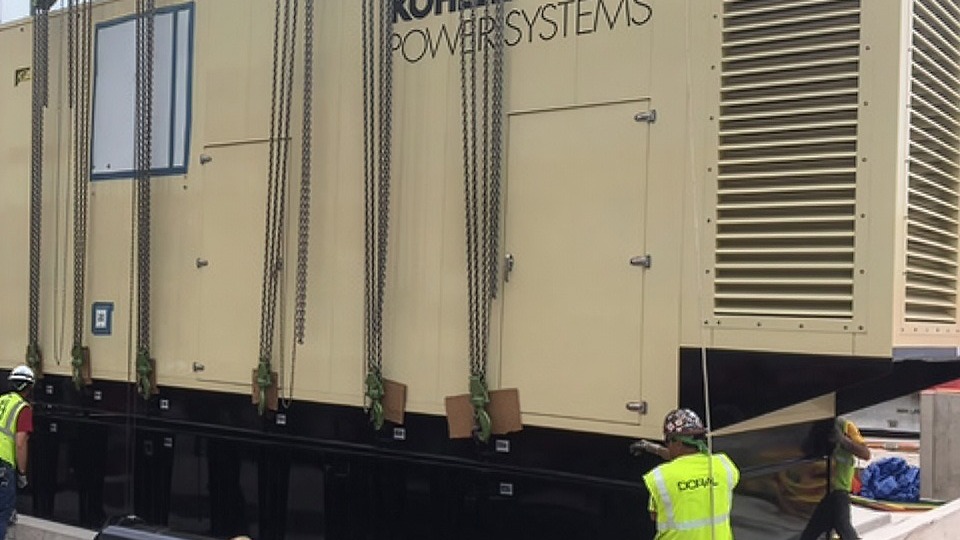 Rehllko generator ready to be lifted by a crane in a professional sports arena.