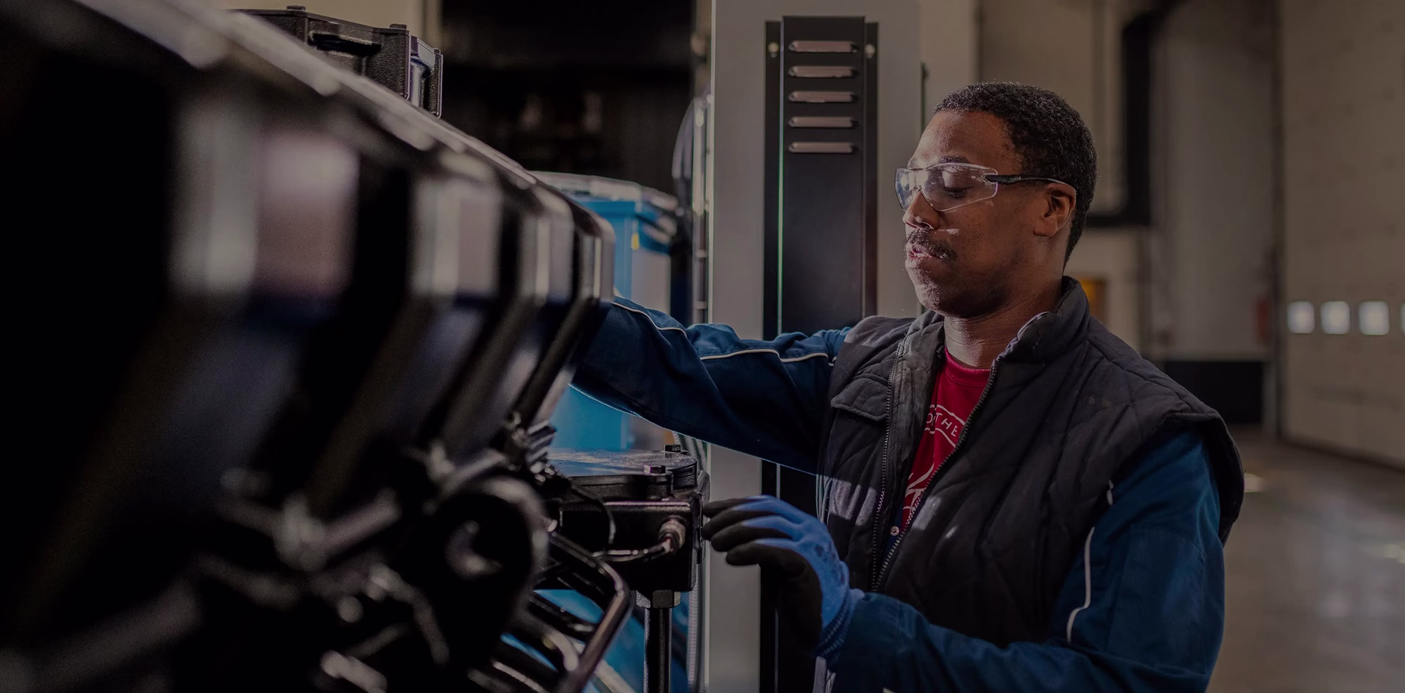 Technician with safety glasses looking at generator parts