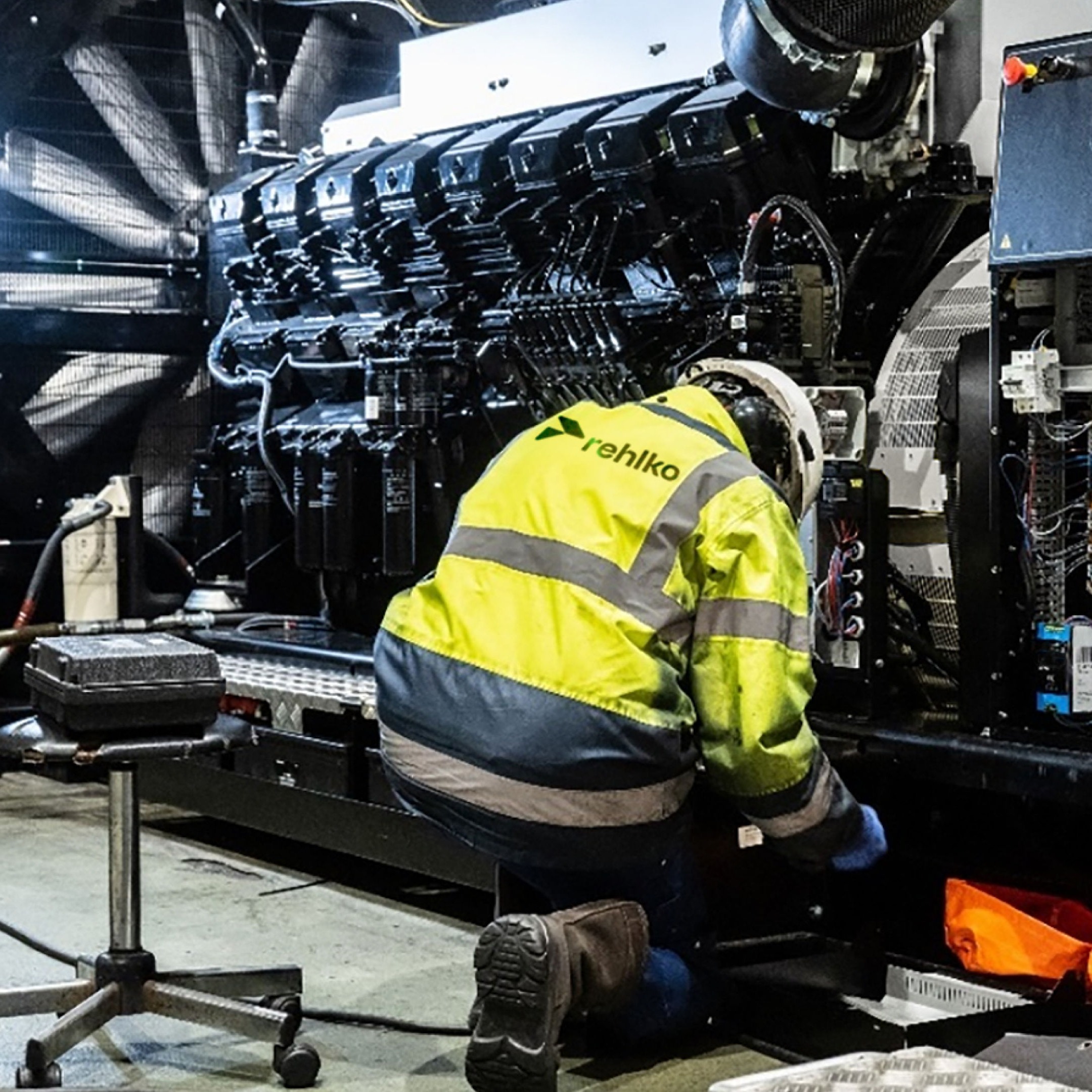 Man in safety jacket on his knees in front of a machine on a factory floor
Distributors