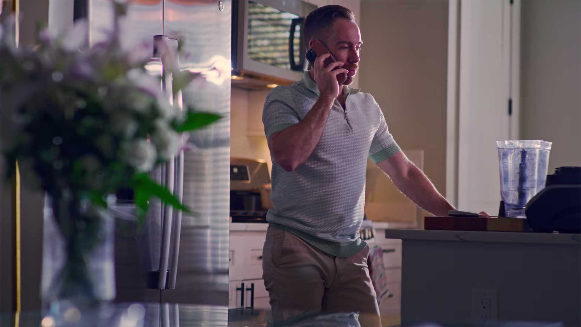 Man talking on a mobile phone by a kitchen counter