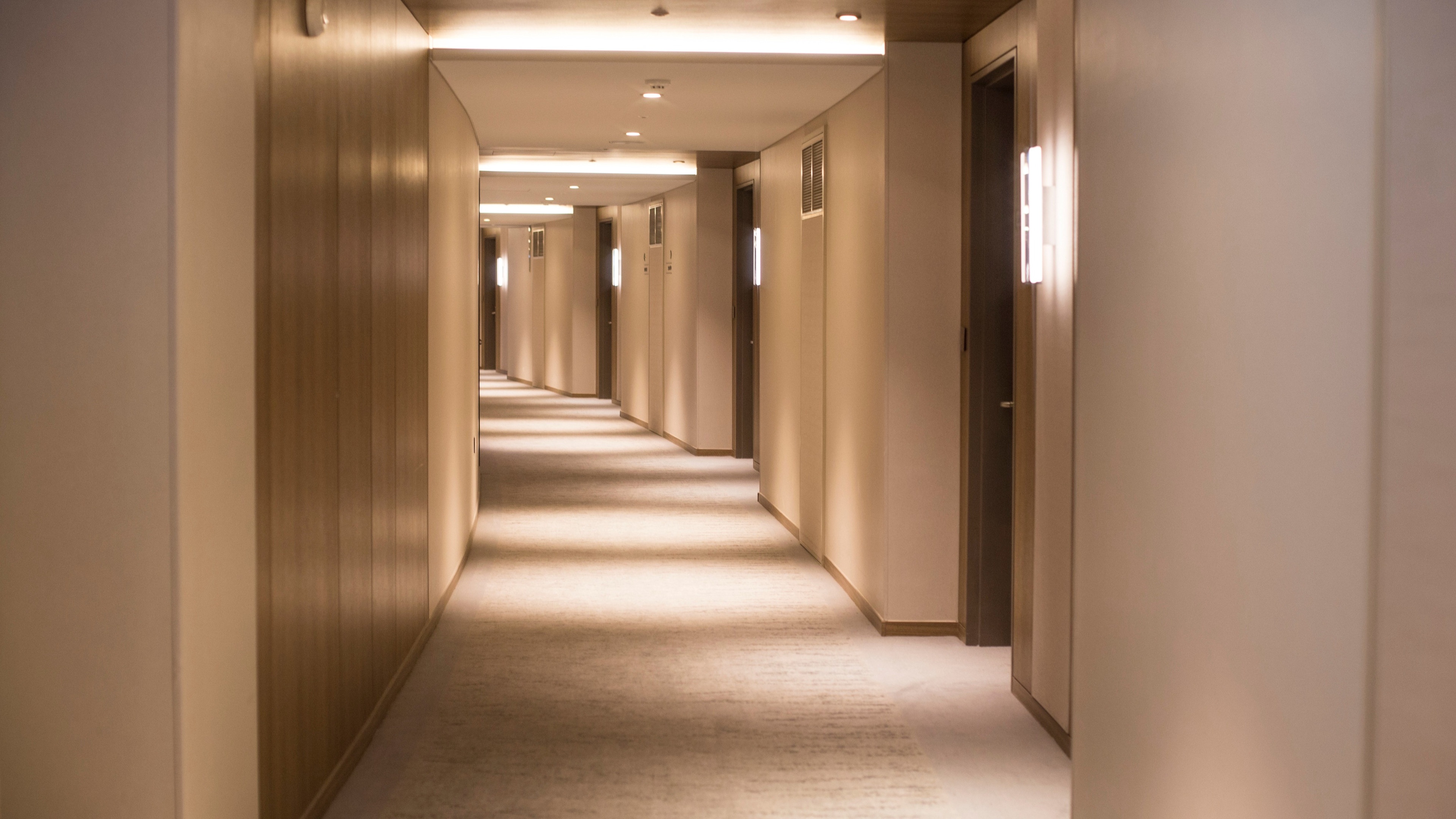 Sepia-toned photo of a hotel hallway with multiple doors and soft lighting.