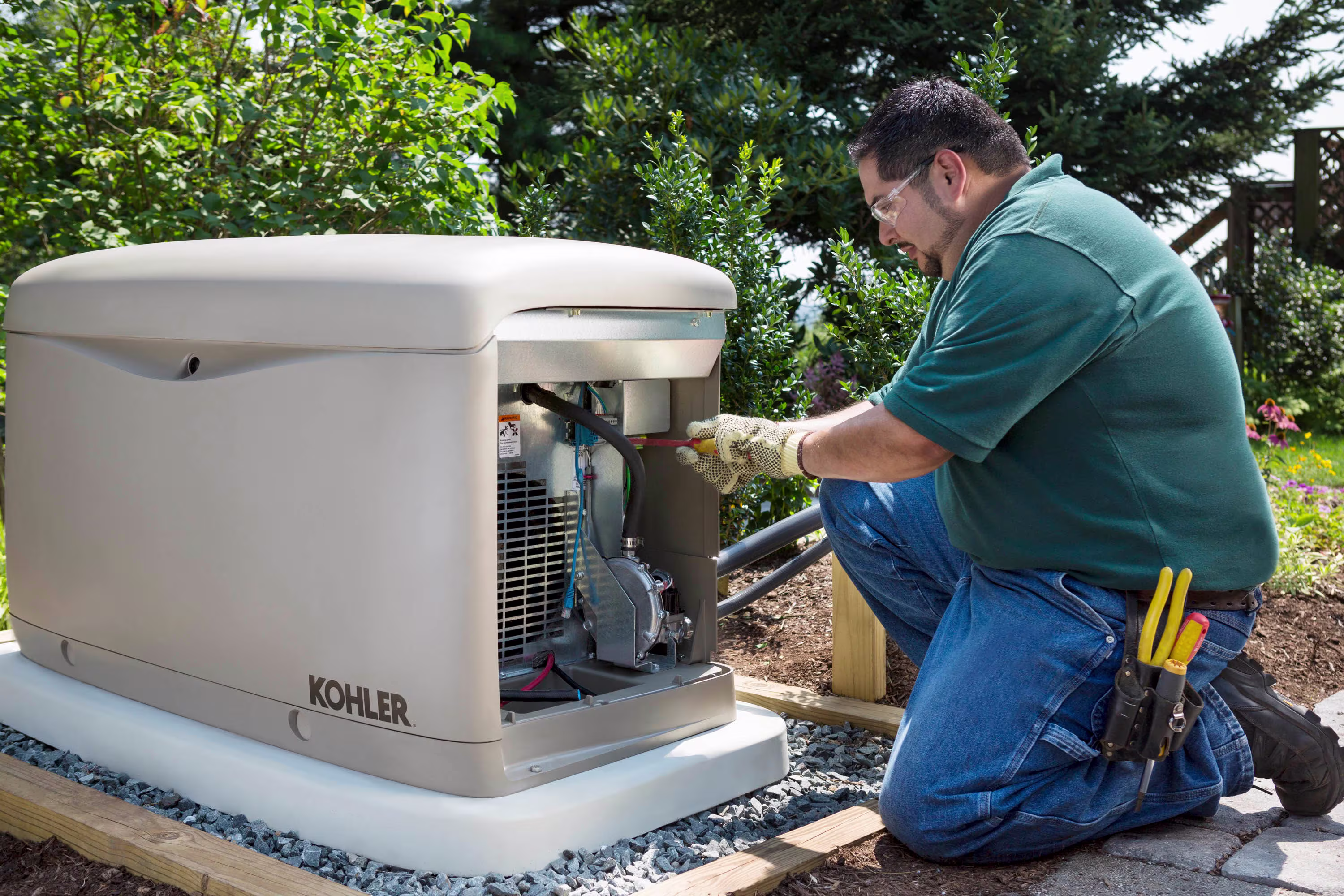 Man wearing safety gear while installing or maintaining an open home generator in a garden.