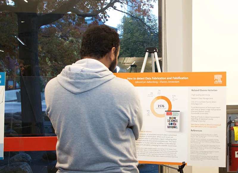 A Harvard student studies the poster on "Research Integrity: How to Detect Data Fabrication and Falsification"