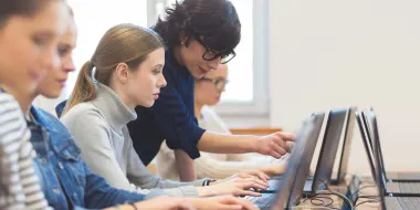 Instructor with students looking at computer monitors