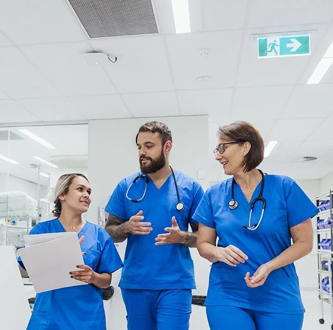 Group of nurses talk while walking through hospital corridor