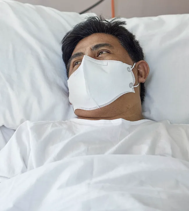 man in hospital bed wearing mask