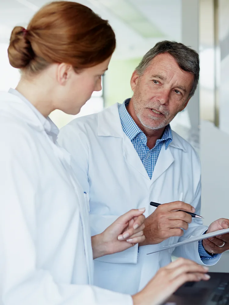 Three pharma professionals discussing research findings in lab coats