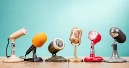Retro old microphones for press conference or interview on table with blue background
