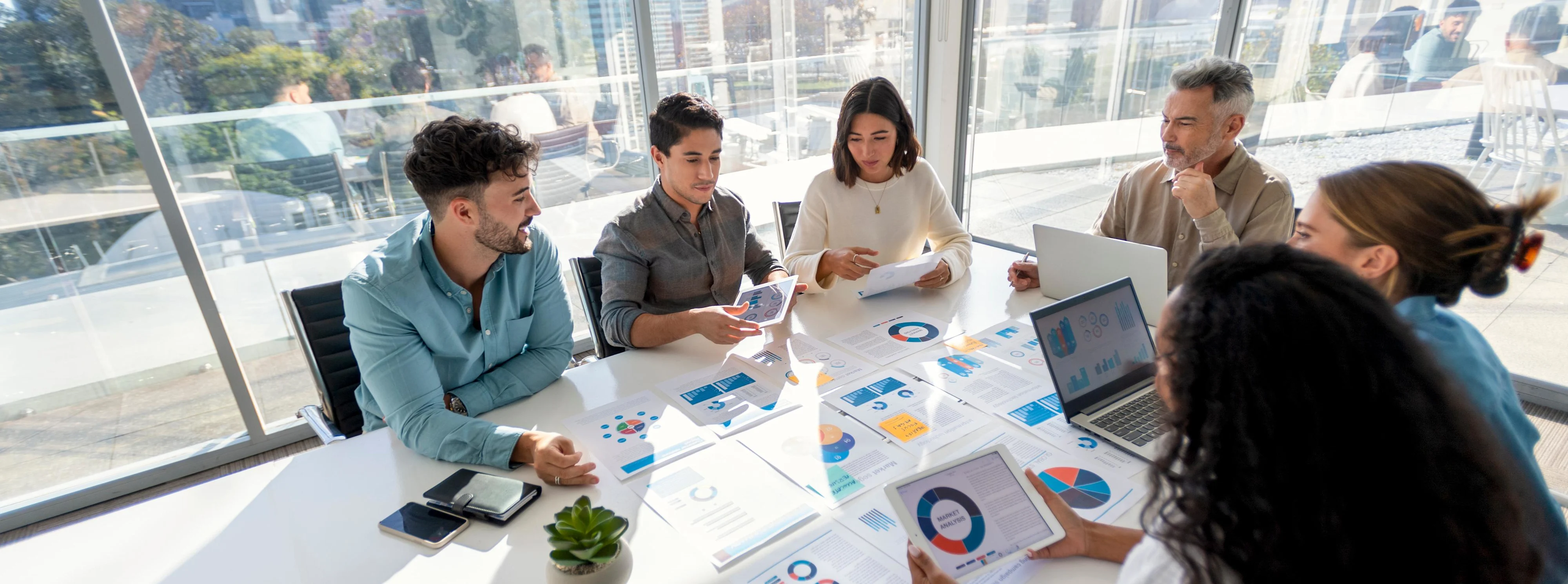 Multi racial group of people working with Paperwork on a board room table at a business presentation or seminar.