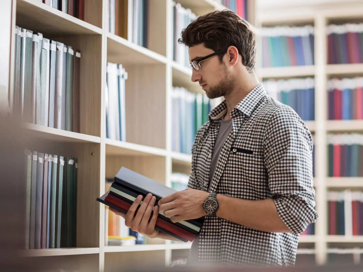 Young man at a library holding books 