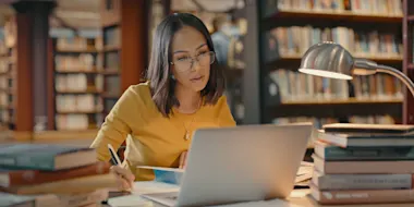 Female alone inside a library working on a project