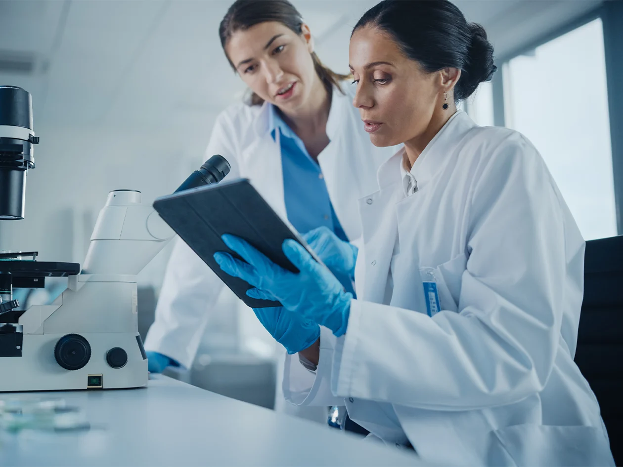 Two Female Scientists Working, Using Digital Tablet, Analysing Samples, Talking