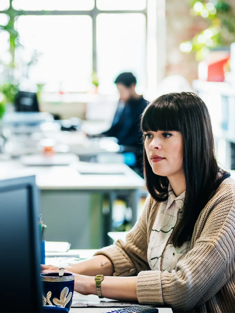 An office worker sitting at her desk working on her computer.