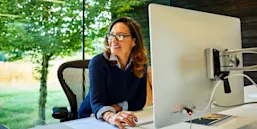 Indoor shot of happy mature businesswoman sitting at her desk and looking away in office