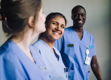 Three health professionals in scrubs smiling