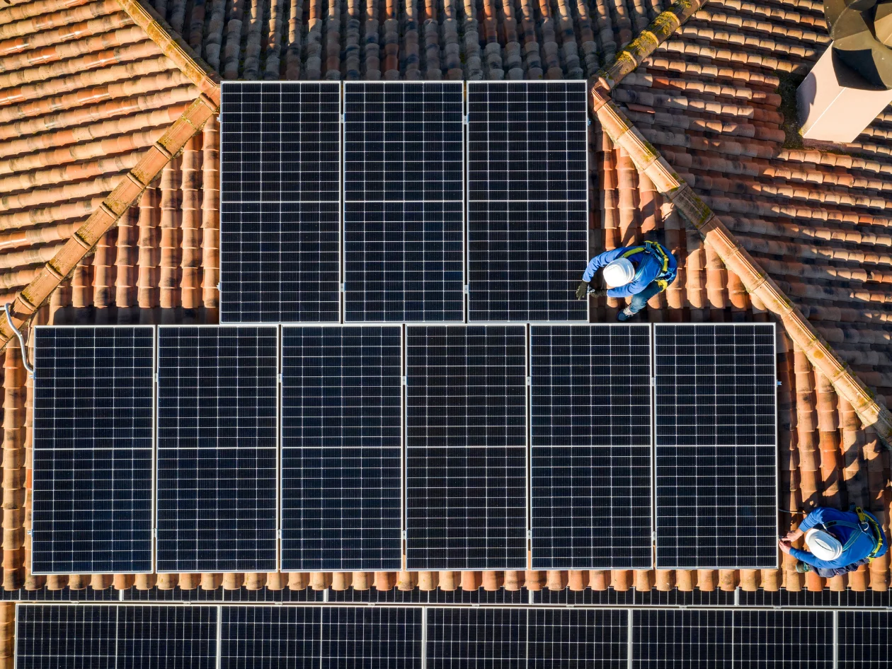 Aerial view of two individuals installing solar panels 