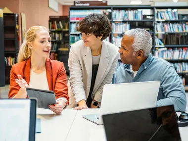 Photo depicting colleagues collaborating in a library (© istock.com/sanjeri)