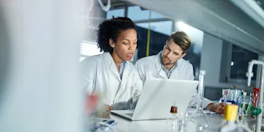 Photo depicting two pharmaceutical researchers working at a computer. (Source: skynesher/E+ via Getty Images)