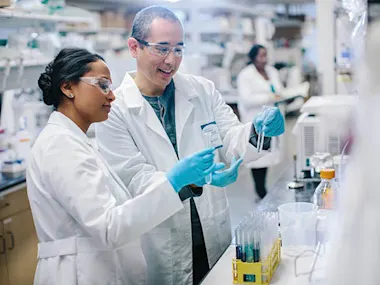 Doctors examining test tubes while coworker working in background at laboratory (Cavan Images/Cavan via Getty Images)