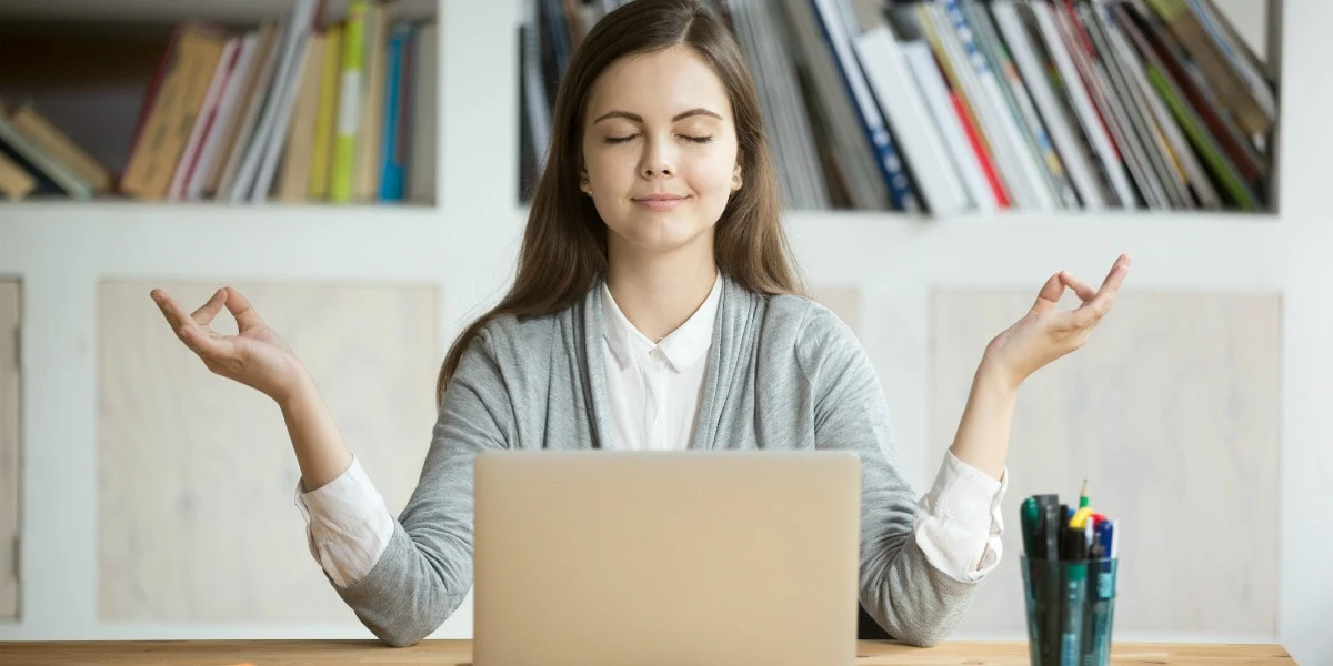 woman meditating in front of a laptop