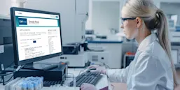 A woman sitting at a computer in a laboratory looking at a web page for Cell Press