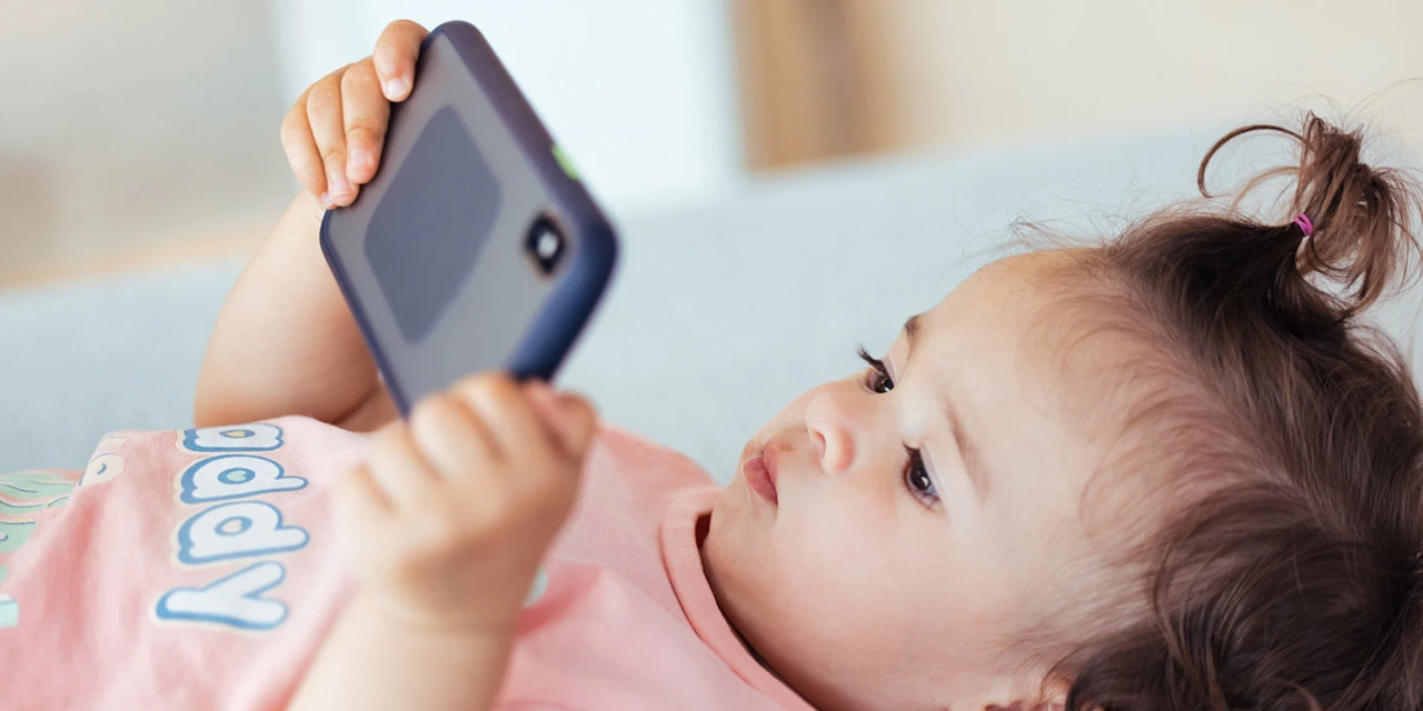 Photo of a toddler peering at the screen of a smartphone. Photo: GCShutter/E+ via Getty Images