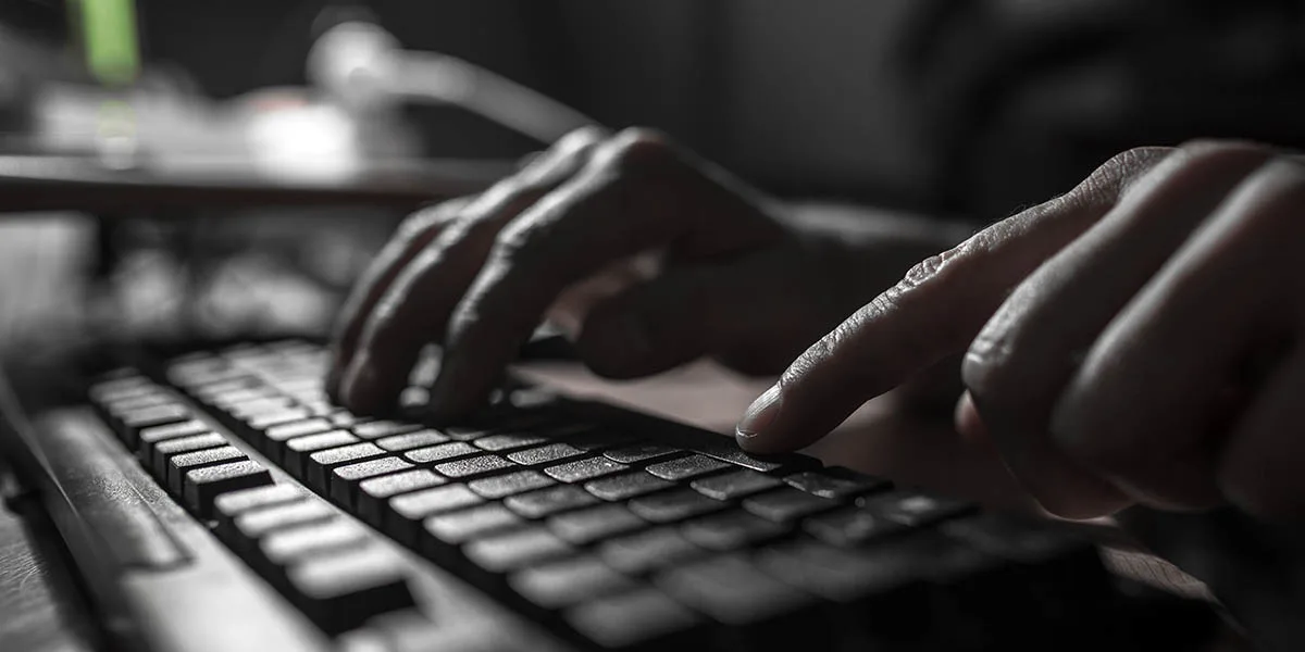 Darkened photo of hands typing on keyboard