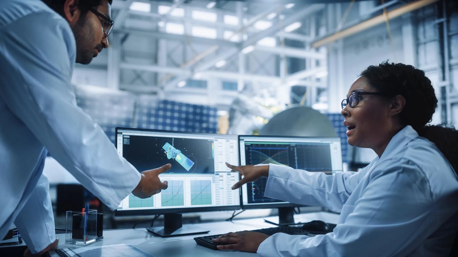 Managing Engineer and Chief Technician Working on Satellite Construction, Talk, Use Computer. Aerospace Agency Manufacturing Facility: Scientists Assemble Spacecraft for Space Exploration Mission